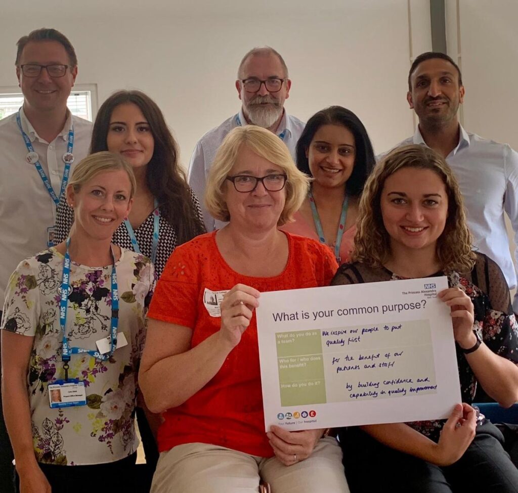 Hospital staff holding "what is your common purpose" team initiative.