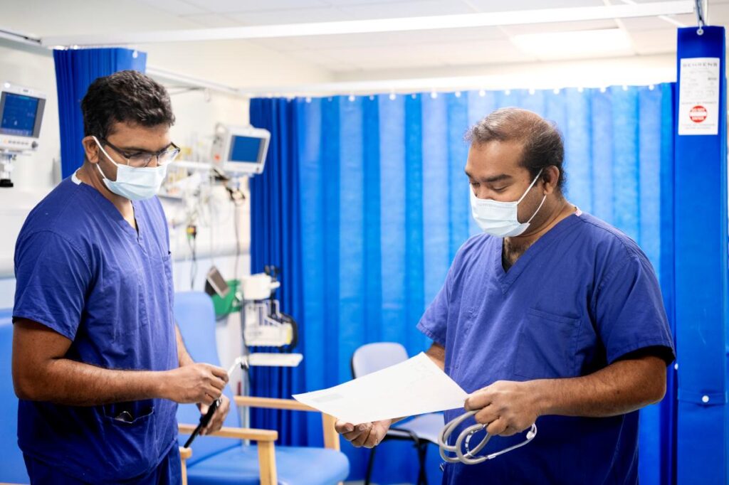 two male trainees in hospital room discussing paperwork