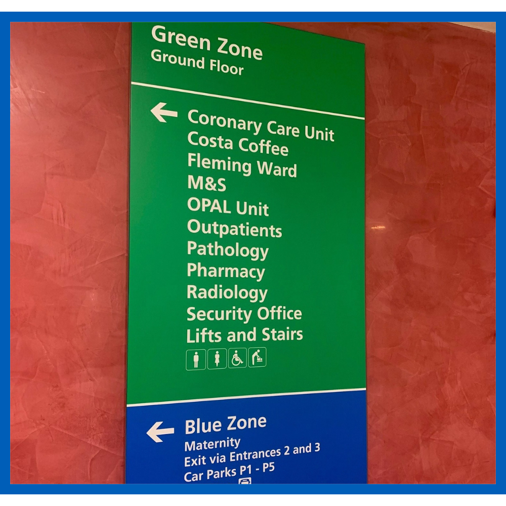 Sign inside the main reception guiding visitors to the green and blue zones with departments listed