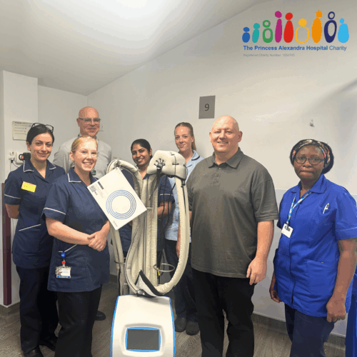 A patient who has fundraised standing with the cancer services team presenting the new scalp cooling machine.