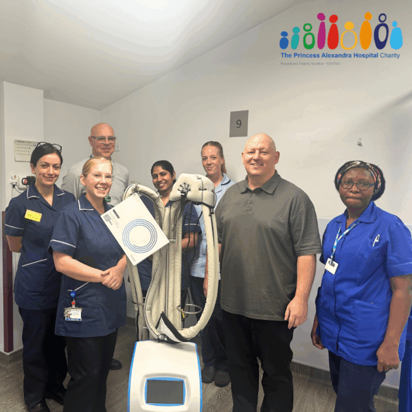 A patient who has fundraised standing with the cancer services team presenting the new scalp cooling machine.