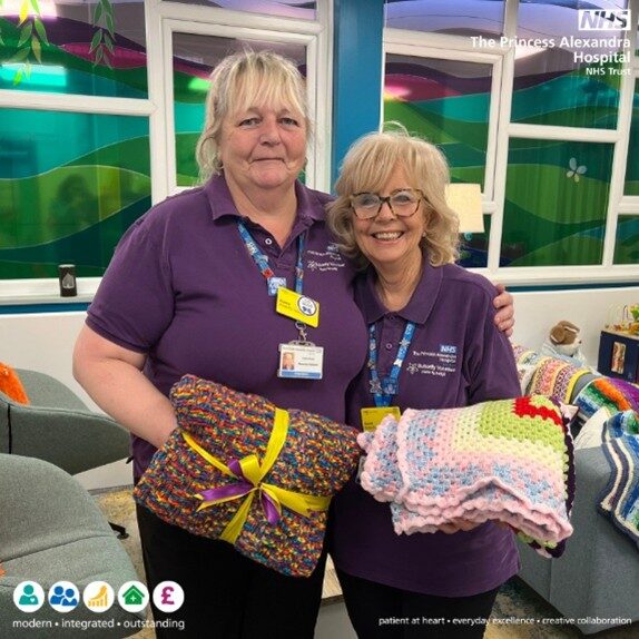 Two of the Butterfly volunteers pictured holding blankets donated to the hospital
